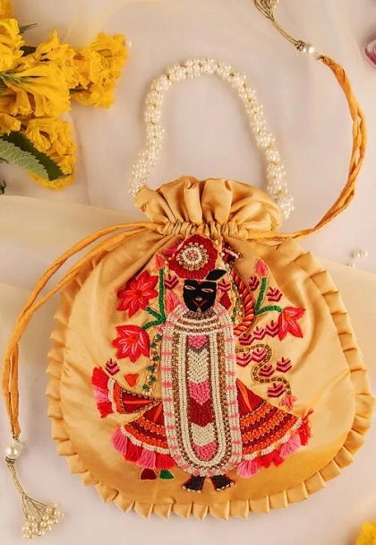 मखमली या सिल्क फैब्रिक पर सुंदर फ्लोरल कढ़ाई वाली पोटली दिन की शादी या हल्दी, मेहंदी जैसे फंक्शन में कैरी करने के लिए बेस्ट।